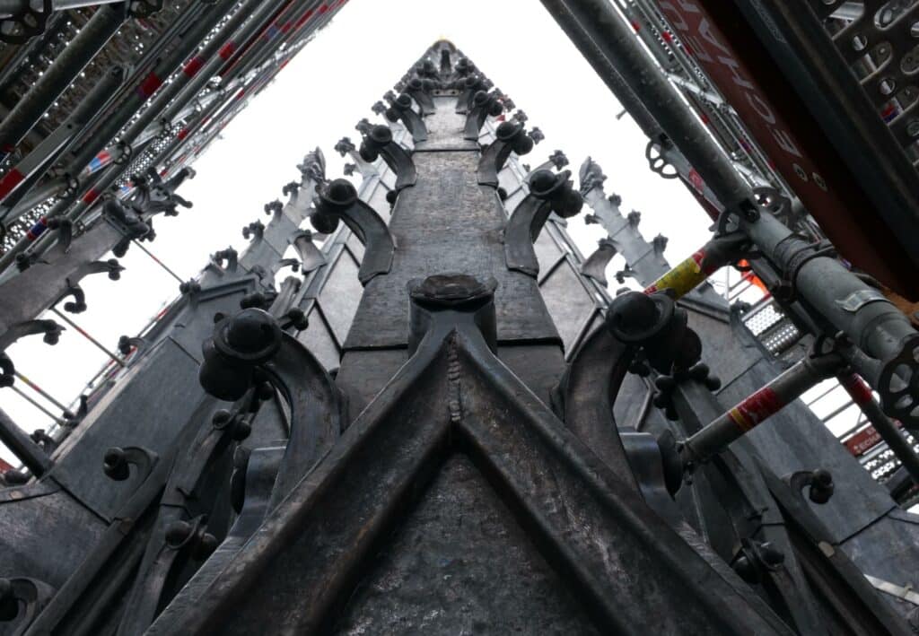 Newly reconstructed spire of Notre-Dame Cathedral with lead roofing and ornamental hooks.